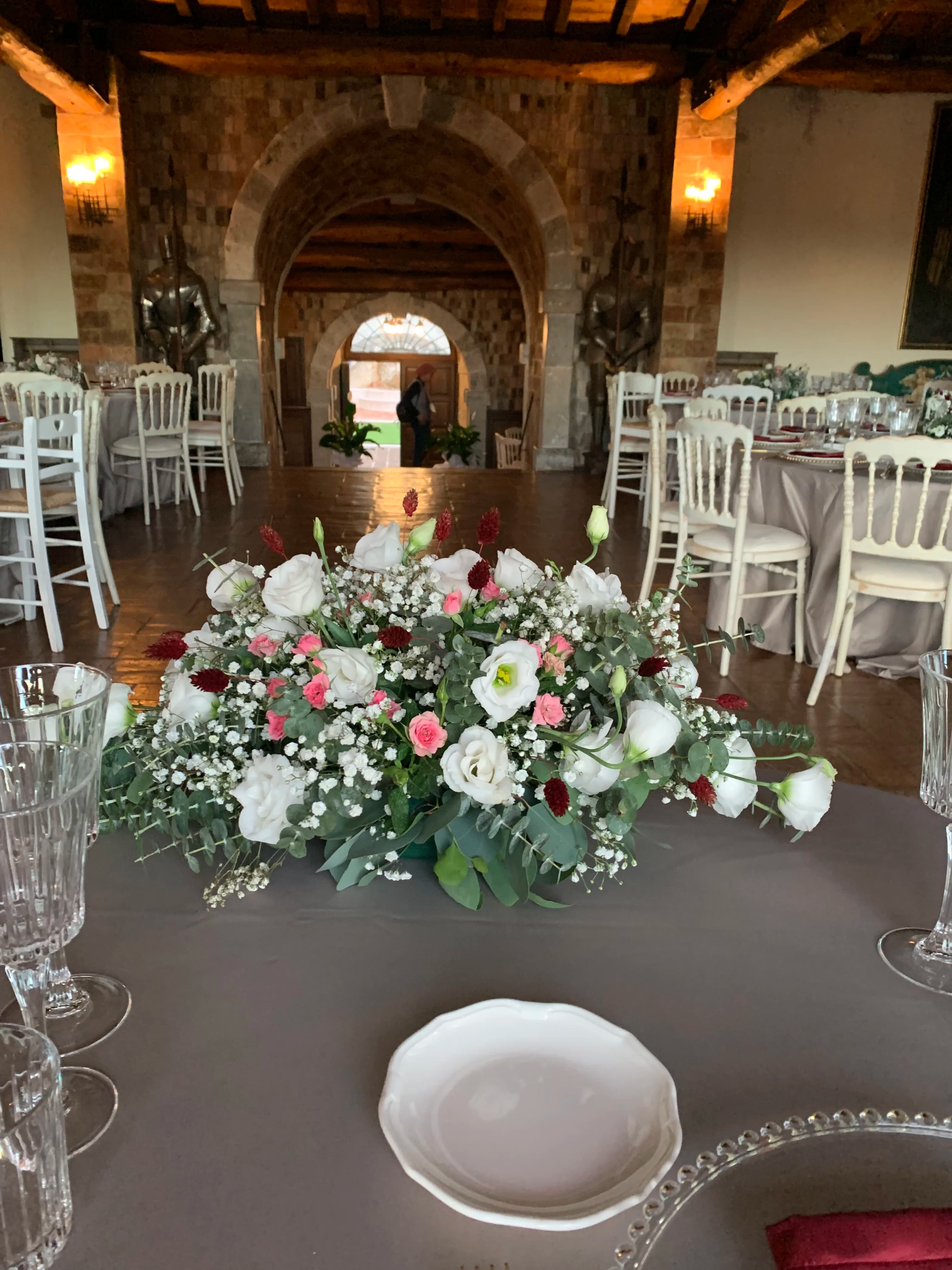 Centrotavola di rose bianche e rosa per un ricevimento di matrimonio in sala rustica