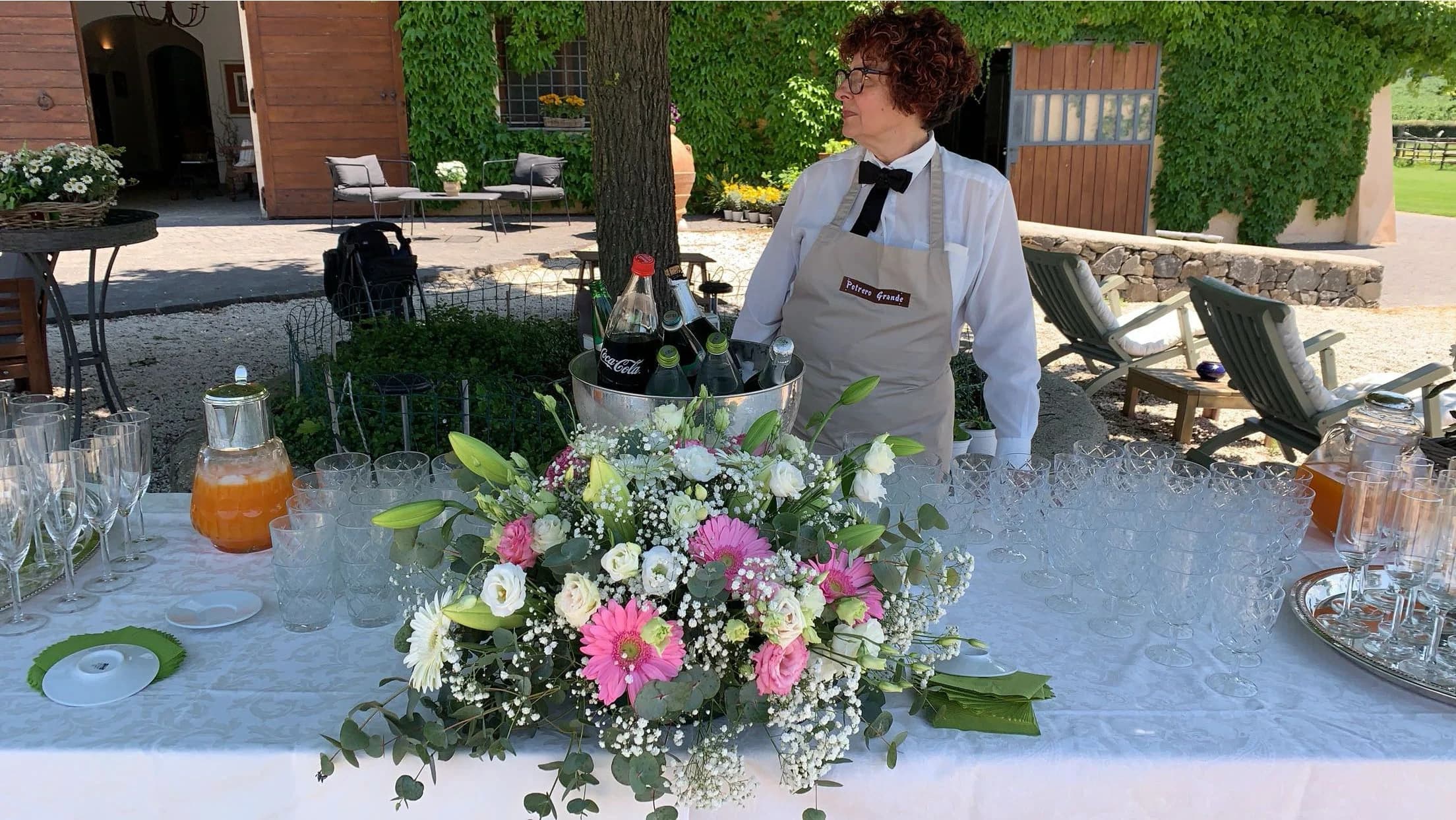 Buffet allestito con centrotavola floreale rosa per un evento all'aperto